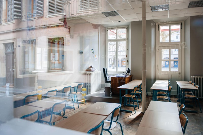 View from the street of large school classroom with empty seats - reflections of city in the window