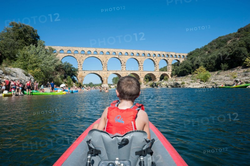 A family kayaks down a river on inflatable kayaks in Southern France