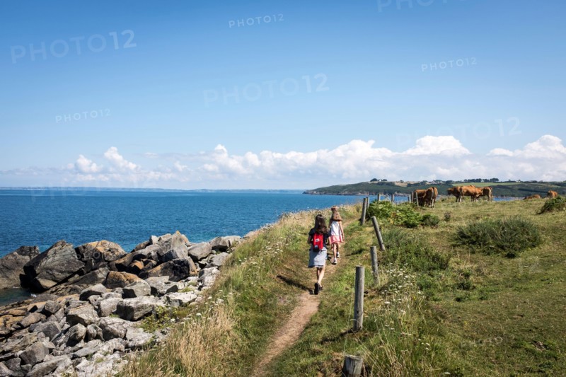A young family walking along the GR34 coastal path between Primel Tregastel and St Jean du Doigt on a beautiful summer day in Britanny, France.