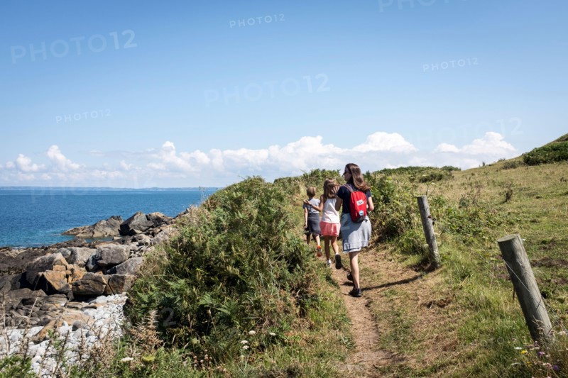 A small family walking along the GR34 coastal path between Primel Tregastel and St Jean du Doigt on a beautiful summer day in Britanny, France.