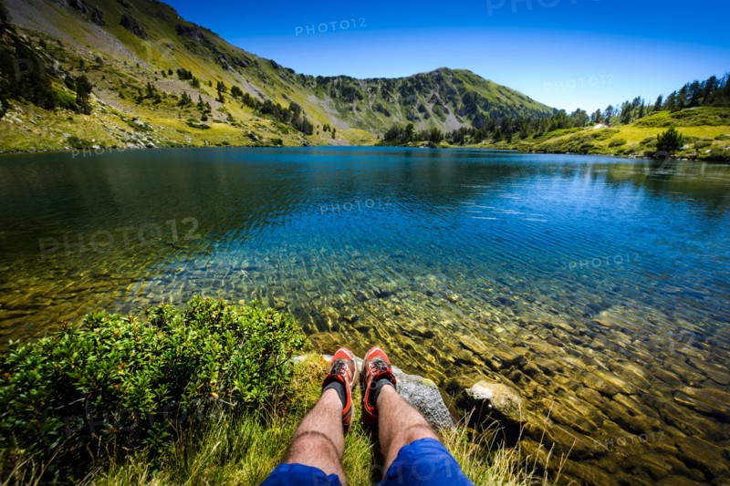 Lake and legs during mountain hiking at Pyrenean mountain