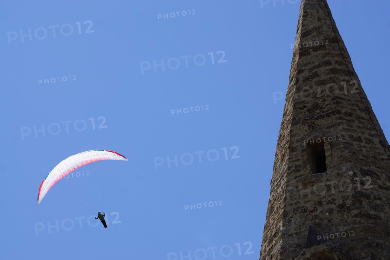 paragliding above an old stone church in the alps france