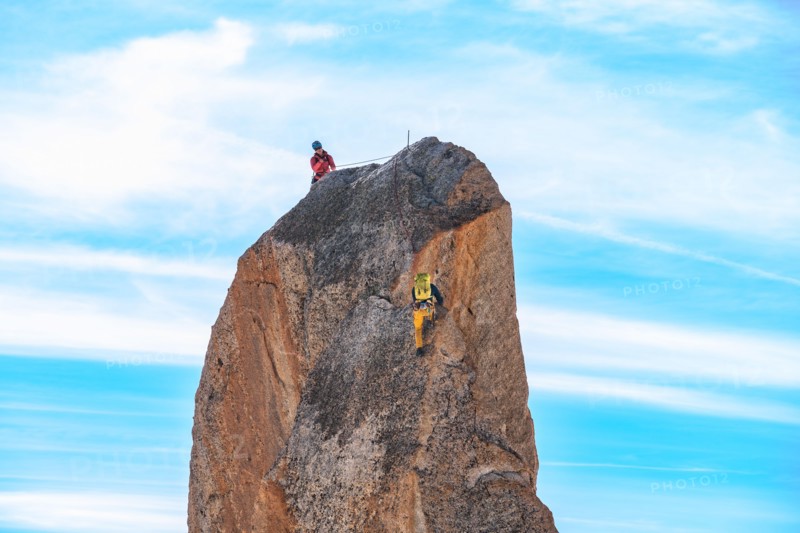 Climbers climbing a large rock on the summit of Aiguille du Midi in Mont Blanc, France