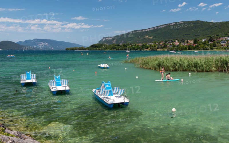 Nautical activities on the clear blue water of Lake Bourget surrounded by the Jura Mountains in the department of Savoie, France.