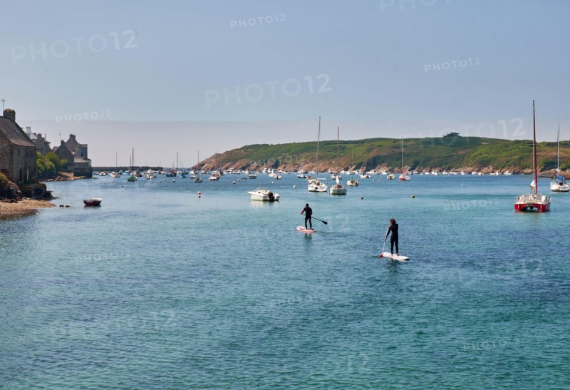 Two people perform paddle boarding in marina in Finister, France
