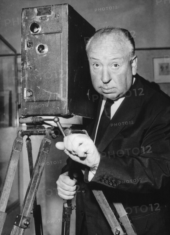 5058144 (900326) Alfred HITCHCOCK, britischer Regisseur, Portrait neben einer Filmkamera. "Jede Nutzung ist honorarpflichtig