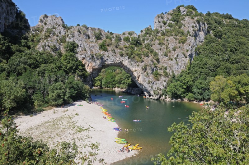 Pont d’Arc rock archway over the Ardeche river Gorges d’Ardeche Gard France with canoes and tourists sunbathing