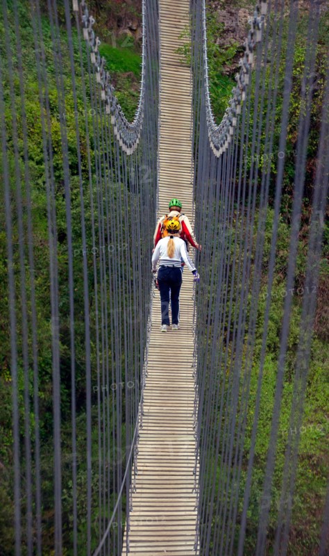 two hikers walking a suspension bridge, France, Mercantour National Park, Lantosque