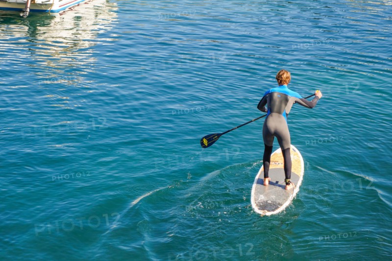 Man paddle boarding, Paddleboarding, out of old port of Biarritz, France.
