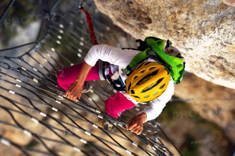 climber at a rock wall with steel net, Via ferrata Escale a Peille, France