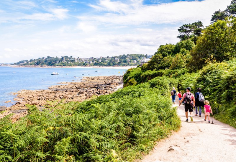 A family with children is walking towards Perros-Guirec on the "sentier des douaniers", the GR34 coastal path along the Pink Granite Coast in Brittany