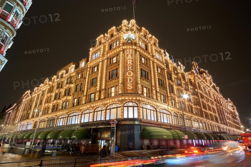 Exterior view of Harrods Department Store in London at night during Winter period. Night traffic street scenery in a typical rainy day.