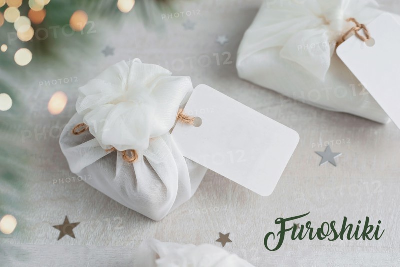 Christmas present wrapped with white furoshiki fabric with labels. Eco friendly gift.