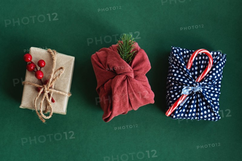 Christmas gifts wrapped in red textile with decor. Sustainable gifts. Zero waste. Xmas eco holiday. Traditional Japanese Furoshiki style. View from above. Flat lay.