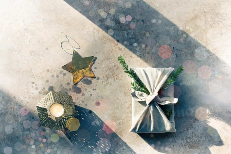 Furoshiki style gift for Christmas or New Year on a white background with bokeh. Flat lay with candle and star.