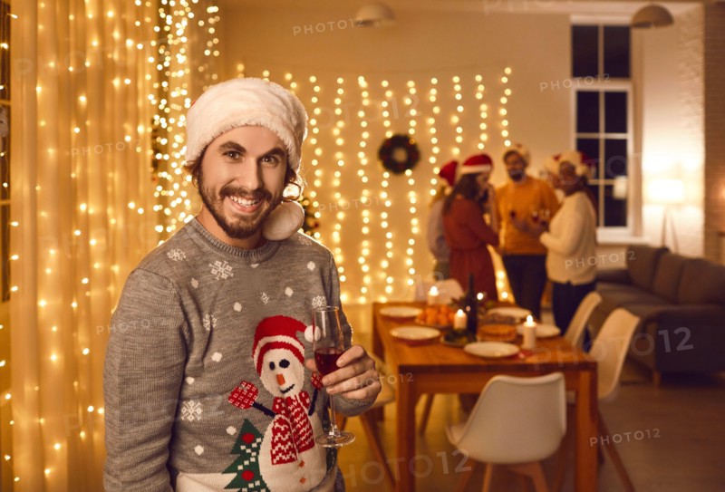 Portrait of happy man in ugly Christmas sweater and Santa hat at Christmas party