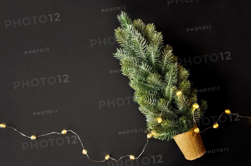 Preparation of decorations for winter celebrations. Artificial Christmas tree, natural jute fiber strip, dark background, cozy lighting