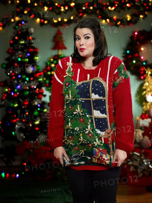 Portrait of woman in ugly Christmas sweater looking at camera surprised.