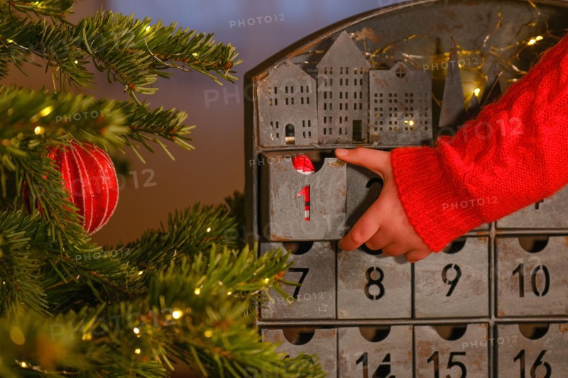 advent calendar.child hand opens the advent calendar near Christmas tree with toys on room background. Christmas traditions and symbols. Gifts and