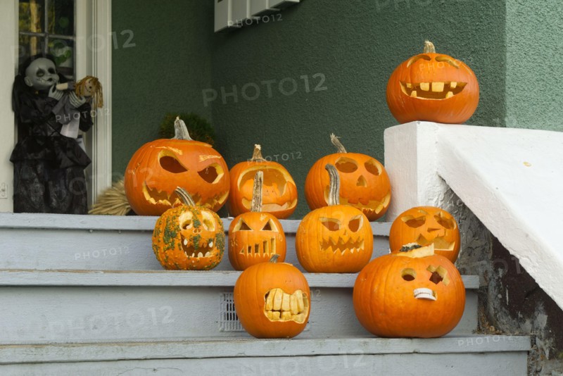Humorous carved Halloween pumpkins displayed on the wooden front stairs of a house