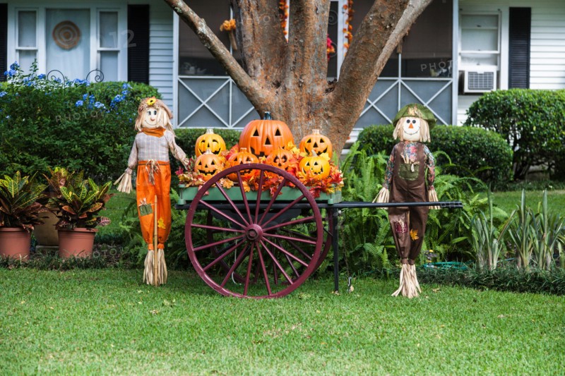 Halloween display of pumpkin jack-o-lanterns and scarecrows on the front lawn of a house