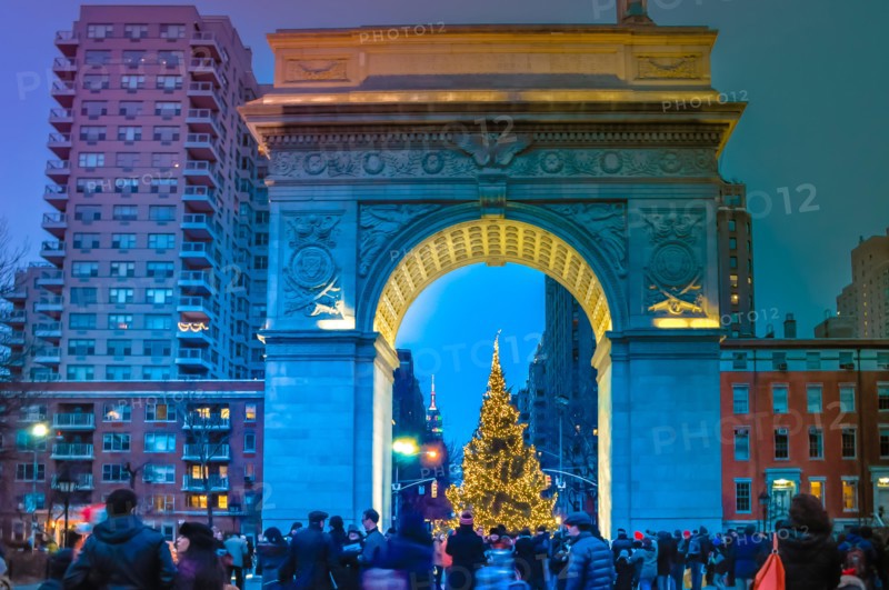 New York City, NY / USA - 12 25 2013: People are walking during Christmas time at Washington Square in Manhattan at night in front of Christmas tree
