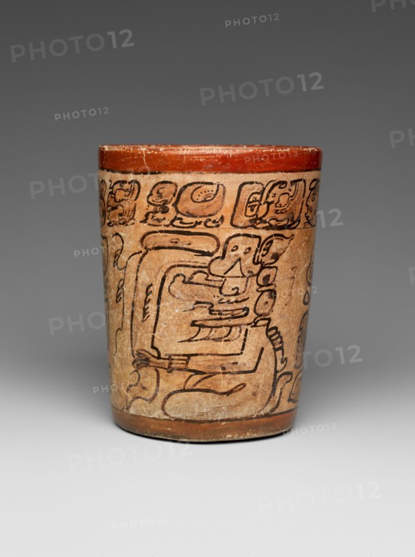 Cylindrical Vessel 7th–8th century Maya This cylindrical vessel framed by red bands contains a hieroglyphic text around its rim and shows two seated gods. It is painted in the ‘codex-style’, and the artist used simple shading to emphasize the two figures. The deities could be a version of K’awiil, the Maya god of lightning, as evidenced by the smoking scrolls emerging from their foreheads. ‘Codex-style’ pots are so-called for the style of painting which bears a close resemblance to the four extant screen-fold Maya books, known as codices, located in Madrid, Paris, Dresden, and Mexico City. The