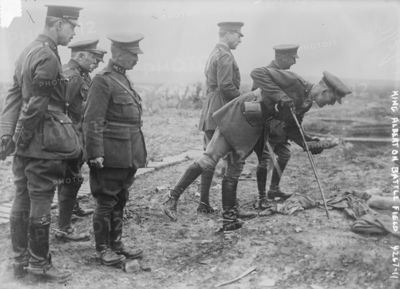 King Albert on Battle Field, Photograph shows an aide-de-camp of King Albert I of Belgium picking up a souvenir on the Somme battlefield near Pozieres, France, May 16, 1917. King Albert I and General Hubert Gough, the British Commander of the Fifth Army stand in background., 1917 May 16, World War, 1914-1918, Glass negatives, 1 negative: glass