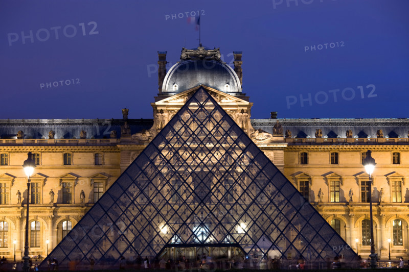 The Louvre Museum illuminated glass pyramid entrance Paris France