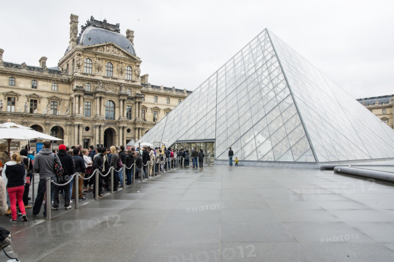 Visitors and tourists queue at the glass pyramid, entrance to the Louvre Museum Paris, France