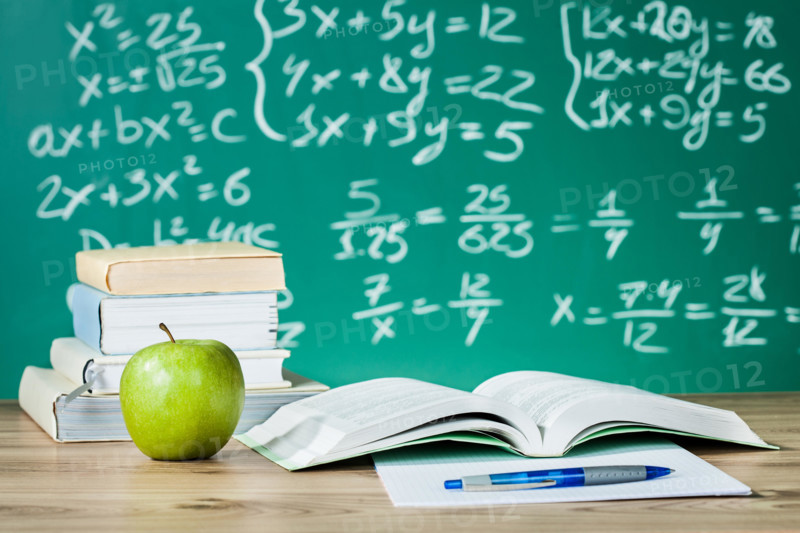 School textbooks on a desk in front of blackboard
