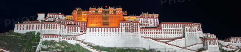 Panorama of Potala Palace at night (Lhasa, Tibet). Black sky, the palace is illuminated. On top of the home of the Dalai Lama waves the Chinese flag.