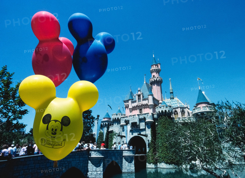 Brightly-colored balloons with the face of Mickey Mouse float in front of Sleeping Beauty Castle, an imposing fairy-tale structure that is the centerpiece of the world’s most famous theme park, Disneyland, which opened in 1955 in Anaheim, California, USA.  The building was modeled after a real castle, Neuschwanstein, constructed in Germany in the late 1800s as a palace for King Ludwig II of Bavaria.  Disneyland was the creation of Walt Disney, a well-known American entrepreneur and filmmaker who created Mickey Mouse and other iconic cartoon characters.