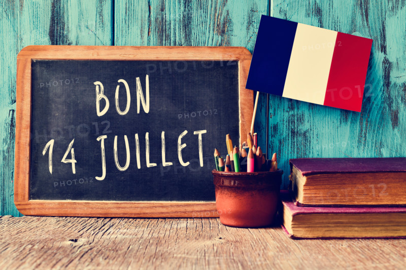 a wooden-framed chalkboard with the text bon 14 juillet, happy 14th of July, the National Day of France, written in French and a
