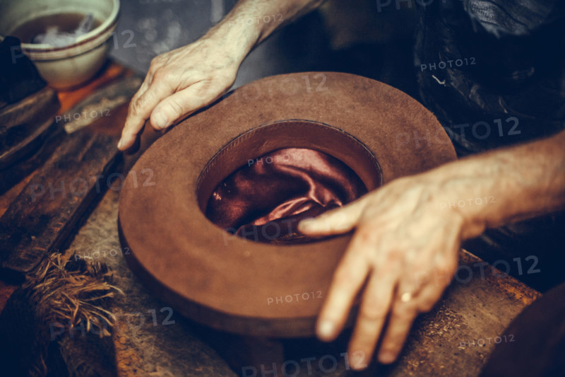 Close up shot of a hatter's hands, manufacturing a hat.