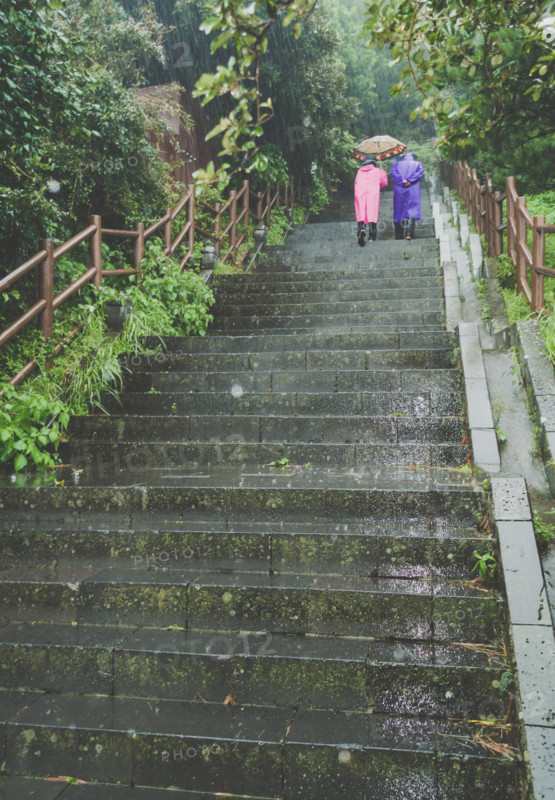 senior couple in colorful raincoats is going upstairs on rainy day