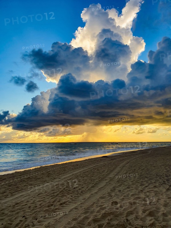 Fluffy clouds above Grand Bahia Principe's beach with sea storm in the far away background, Punta Cana, Dominican Republic.