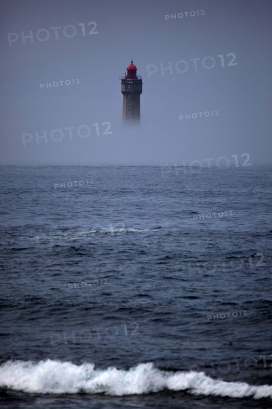 The dramatic La Jument lighthouse, shrounded in summer fog, off the coast of the Ile d'Ouessant, Brittany. The iconic 47-metre high lighthouse was bui
