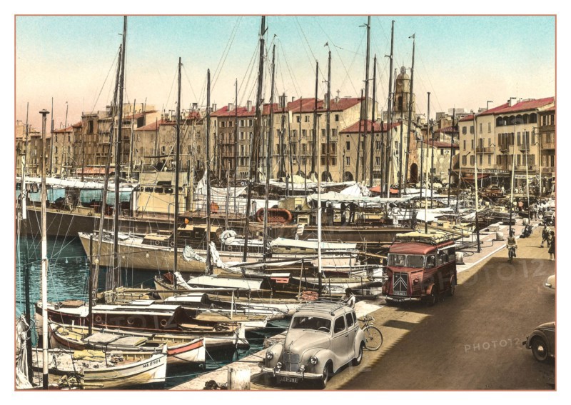 ST.TROPEZ Vintage 1950’s 1960's View of the harbour with fishing and sailing boats moored with French Citroen Van and Peugeot Motorcar parked, cafes and restaurants behind. Côte d’Azur South of France Riviera.  Saint-Tropez picturesque, cafe & shop-lined harbour port and a popular trendy chic fashionable sailing & luxury yacht destination.