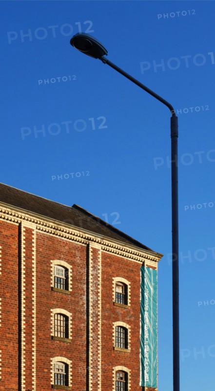 A classic street lantern embraces a stone building with bricks, against the background of the blue sky, Greenock, Scotland