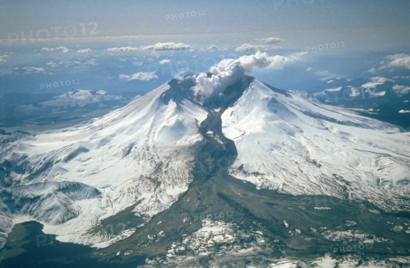 Mount St. Helens erupted often between 1980 and 1986. An explosive eruption on March 19, 1982, sent pumice and ash 9 miles (14 kilometers) into the air, and resulted in a lahar (the dark deposit on the snow) flowing from the crater into the North Fork Toutle River valley. Part of the lahar entered Spirit Lake (lower left corner) but most of the flow went west down the Toutle River, eventually reaching the Cowlitz River, 50 miles (80 kilometers) downstream.
