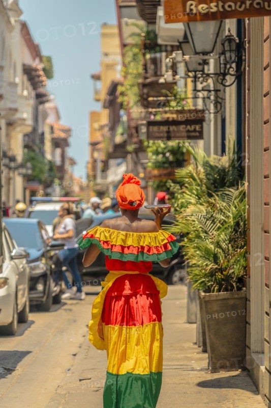 Photograph of a Colombian woman in Cartagena de Indias walking in the Palenqueras dress. Trip to Colombia. Typical colonial colors of the city