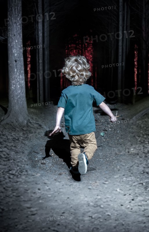 A little boy runs through the night forest after an orange light