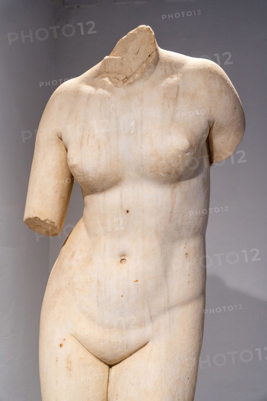 Close-up on beheaded ruins of ancient marble statue portraiting a naked female body