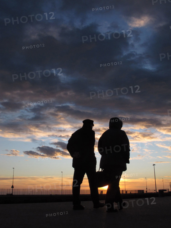 old senior elderly couple silhouette by sea at sunset
