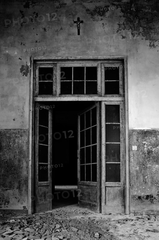 Italy. Abandoned hospital door with cross on the wall