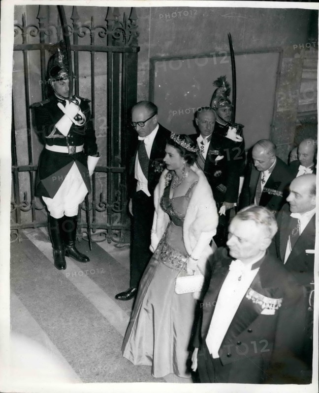 Apr. 04, 1957 - The Queen Attends A Candle-Lit Banquet At The Famous Louvre In Paris. Photo shows Wearing the red sash of the Legion of Honour over her brilliant Kingfisher blue-green dress, the Queen arrives for a candle-lit banquet at the Louvre accompanied by M. Guy Mollet, the French Prime Minister, (left) and M. Pineau (seen behind)