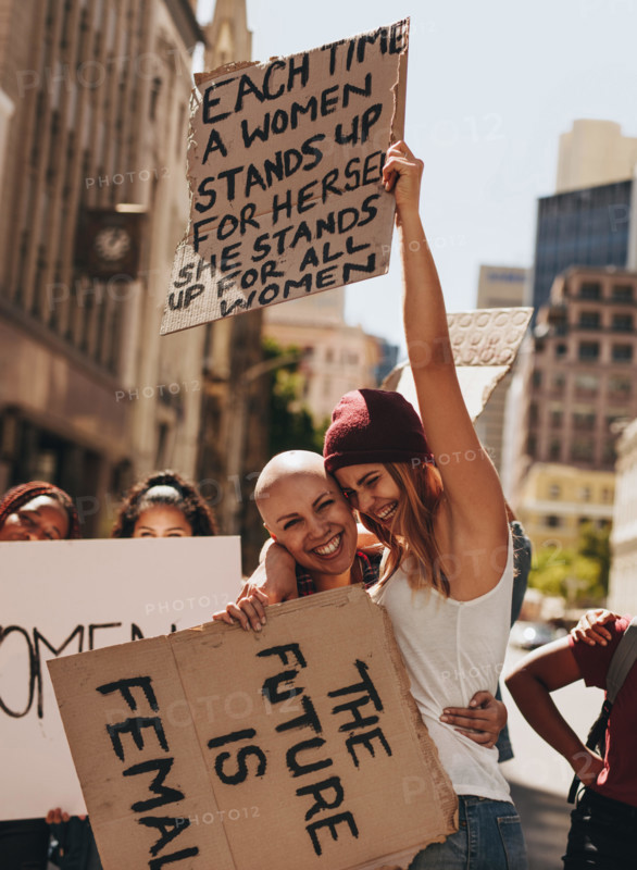 Group of young female activists protesting with signboards on road. Women enjoying during a demonstration on road.