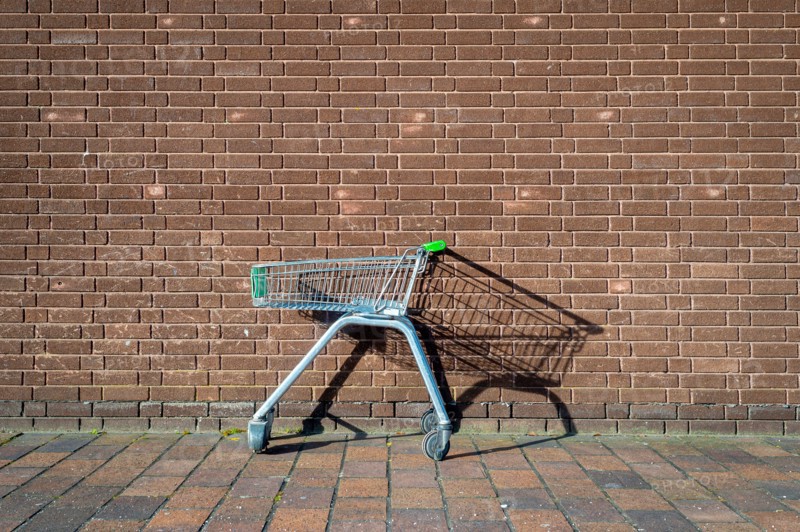 abandoned, empty supermarket trolley by a brick wall, shopping concept.