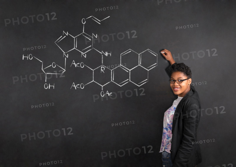 South African or African American woman teacher writing science on chalk black board background